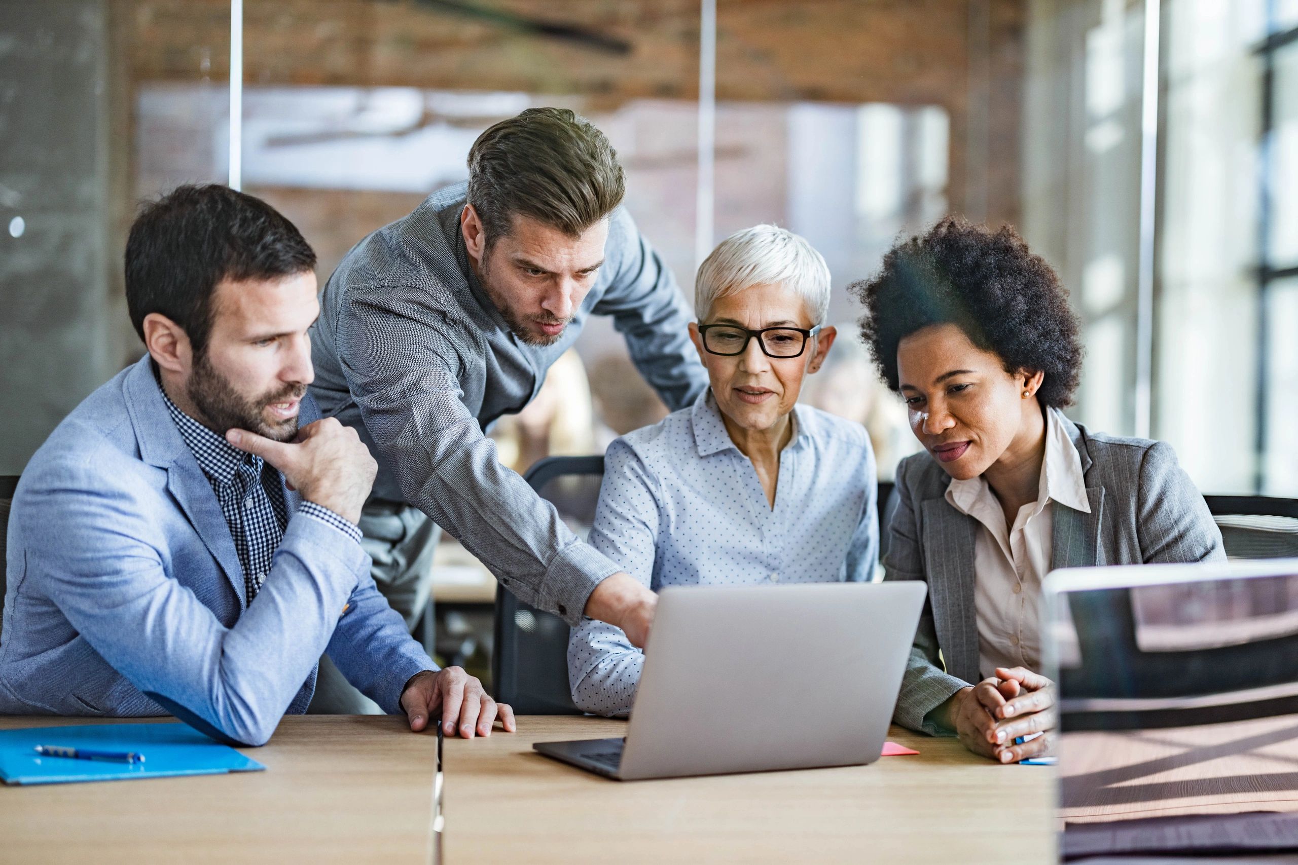 Business team collaborating around a laptop in an office meeting